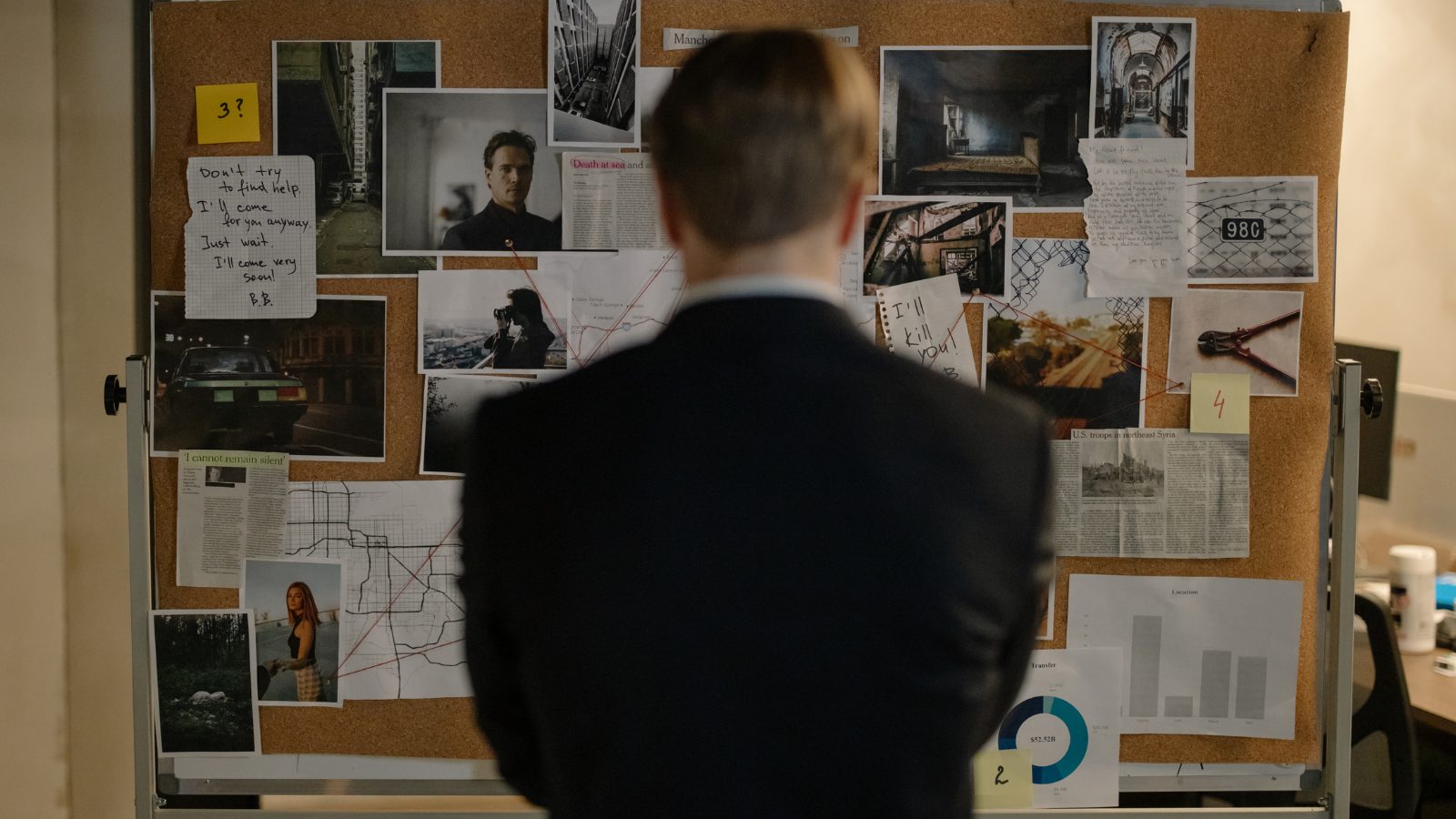 Investigator analysing a case board of cross-referenced evidence, photographs and documents